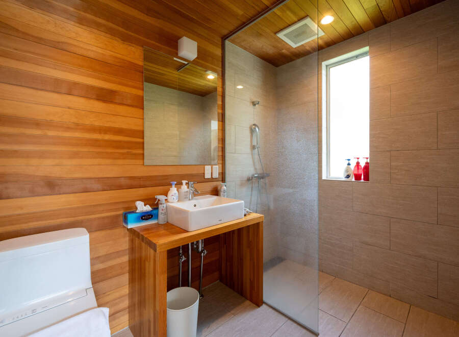 This modern bathroom boasts a sleek design with wood paneling and a glass-enclosed shower.