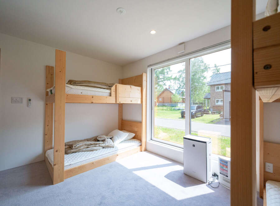 Bright and airy room with a bunk bed and large window overlooking a residential street.