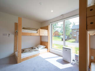 Bright and airy room with a bunk bed and large window overlooking a residential street.
