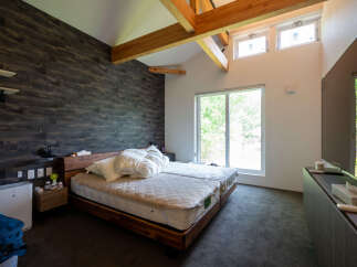 This stunning bedroom boasts a cozy and modern design, featuring a plush bed with a quilted mattress topper and a dark wood frame.