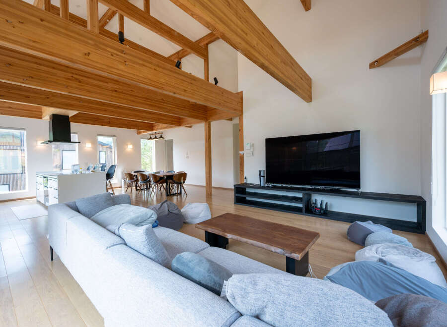 This stunning home boasts an open-concept living area with high ceilings and exposed wooden beams, creating a warm and inviting atmosphere.