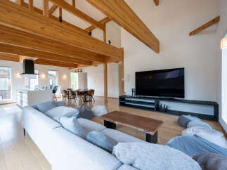 This stunning home boasts an open-concept living area with high ceilings and exposed wooden beams, creating a warm and inviting atmosphere.