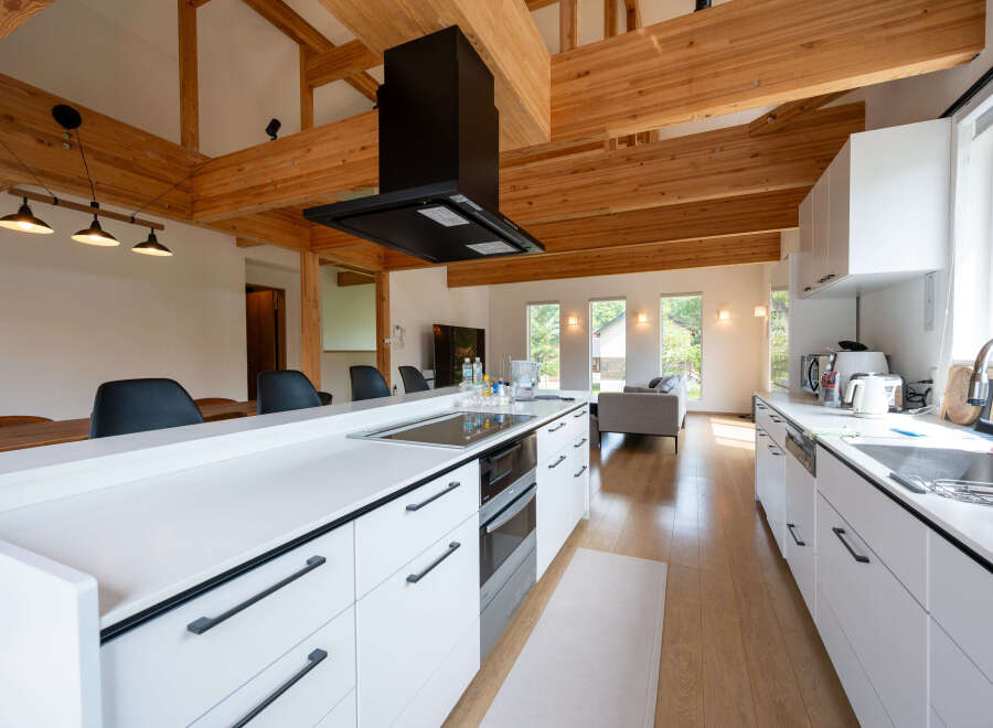This stunning kitchen boasts a spacious island with sleek white cabinetry and modern black hardware.