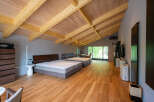 This stunning bedroom boasts a vaulted wood ceiling and expansive windows showcasing lush greenery.