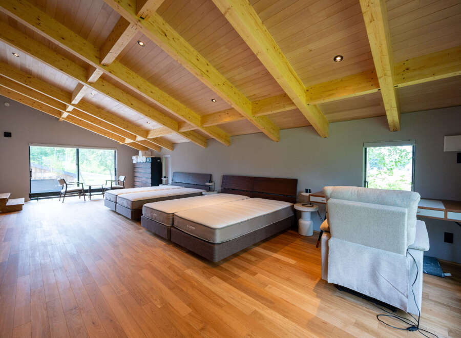This stunning property boasts a spacious open-plan bedroom with high, exposed wooden beam ceilings and large windows offering abundant natural light.