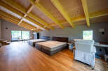 This stunning property boasts a spacious open-plan bedroom with high, exposed wooden beam ceilings and large windows offering abundant natural light.