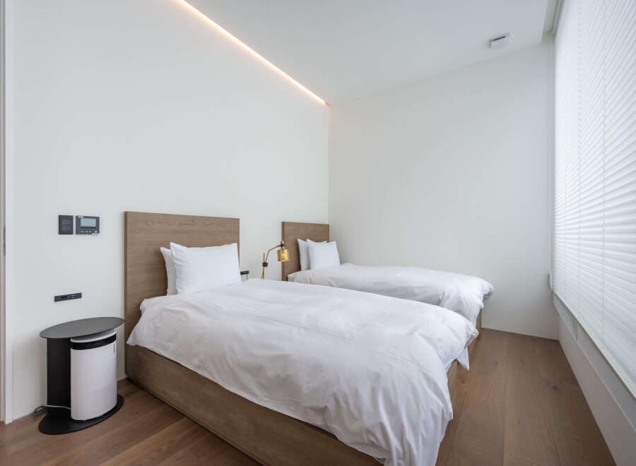 This modern bedroom boasts two twin beds with crisp white linens, perfect for a relaxing stay.