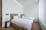 This modern bedroom boasts two twin beds with crisp white linens, perfect for a relaxing stay.