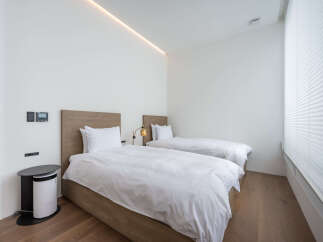 This modern bedroom boasts two twin beds with crisp white linens, perfect for a relaxing stay.