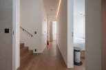 Modern hallway with hardwood floors, sleek staircase, and recessed lighting.
