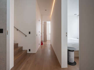 Modern hallway with hardwood floors, sleek staircase, and recessed lighting.