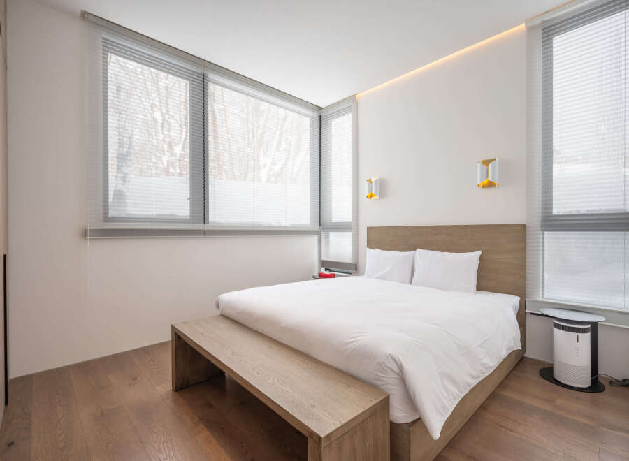 Modern bedroom with large windows offering natural light and views of snowy trees.
