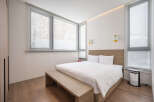 Modern bedroom with large windows offering natural light and views of snowy trees.
