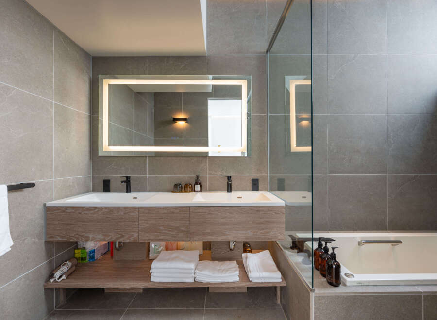 This luxurious bathroom boasts a double vanity with sleek, modern fixtures and ample storage.
