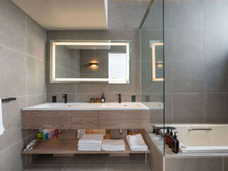 This luxurious bathroom boasts a double vanity with sleek, modern fixtures and ample storage.