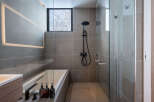 Modern bathroom with a sleek design, featuring a frameless glass shower enclosure, a built-in bathtub, and stylish black fixtures.