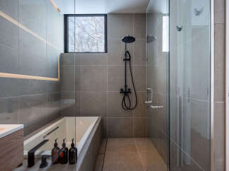 Modern bathroom with a sleek design, featuring a frameless glass shower enclosure, a built-in bathtub, and stylish black fixtures.