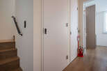 Modern hallway with sleek white doors and dark wood flooring.