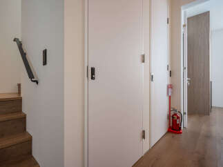 Modern hallway with sleek white doors and dark wood flooring.