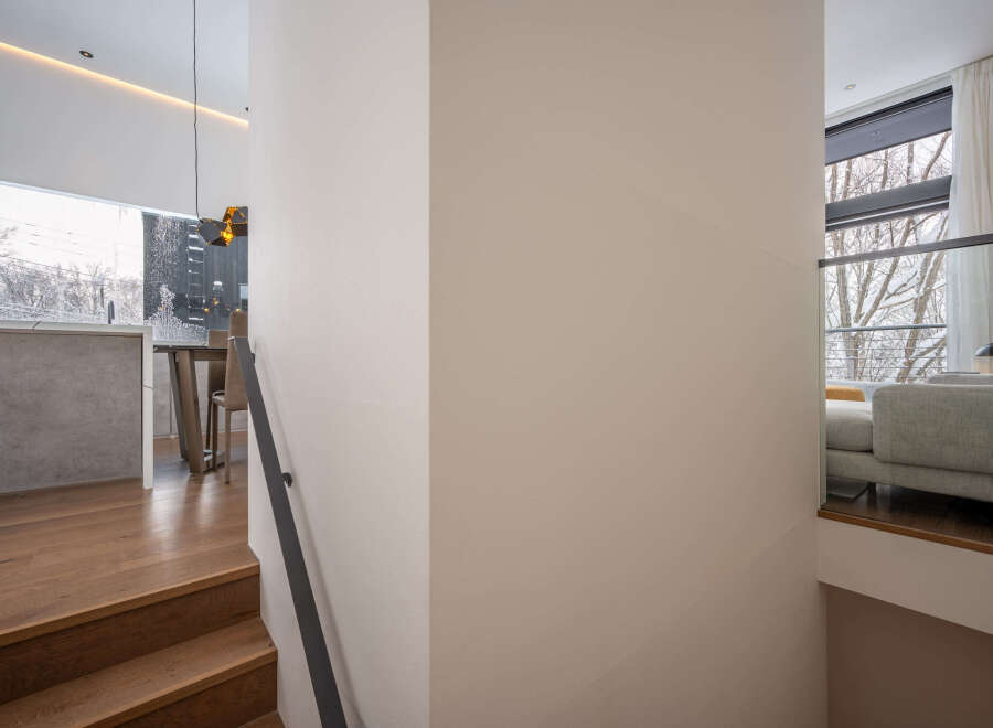 Modern staircase design with sleek metal railing and hardwood steps leading to an open-concept living area.