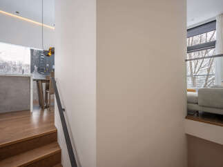 Modern staircase design with sleek metal railing and hardwood steps leading to an open-concept living area.