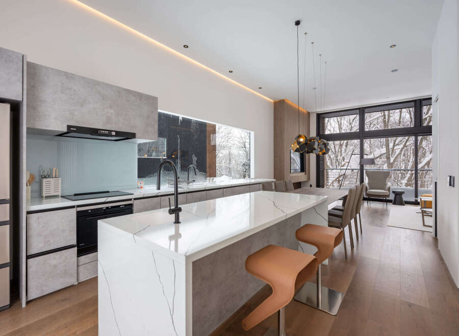 This stunning modern kitchen boasts a sleek design with concrete-look cabinetry and a stunning marble island.