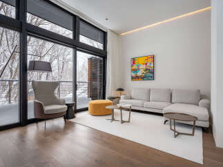 Modern living room with floor-to-ceiling windows offering stunning snowy forest views.