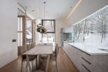Modern kitchen and dining area with stunning views of a snow-covered forest.