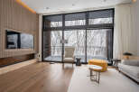 Luxurious living room with floor-to-ceiling windows offering breathtaking snowy forest views.