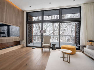 Luxurious living room with floor-to-ceiling windows offering breathtaking snowy forest views.