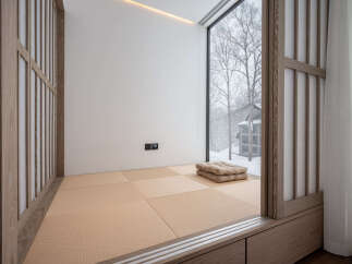 This serene bedroom features a minimalist design with tatami mats, shoji screens, and a stunning view of a snow-covered landscape.