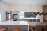 Modern kitchen with marble countertops and a large window overlooking a snowy landscape.