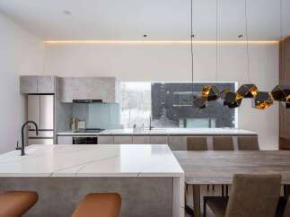 Modern kitchen with marble countertops and a large window overlooking a snowy landscape.