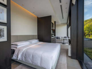 Luxurious hotel room with a king-size bed, stunning mountain views, and a modern kitchenette.
