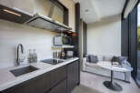 This modern apartment boasts a stylish kitchenette with integrated appliances and sleek dark wood cabinetry.
