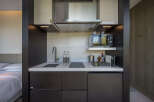 This modern hotel room boasts a compact yet fully equipped kitchenette, perfect for a comfortable stay.