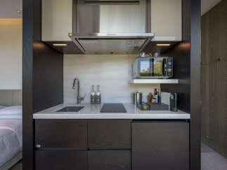 This modern hotel room boasts a compact yet fully equipped kitchenette, perfect for a comfortable stay.