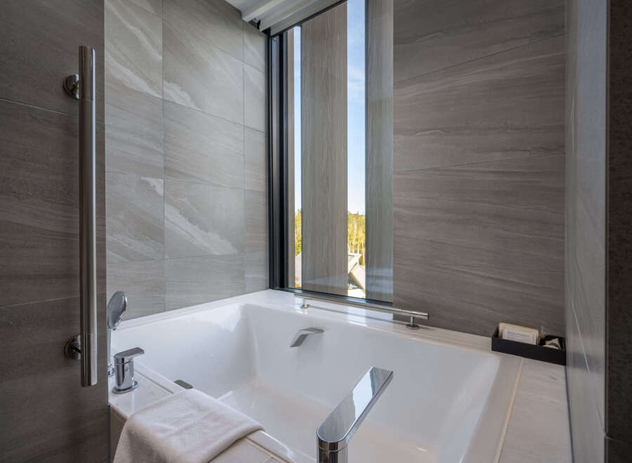 Indulge in tranquility with our luxurious bathroom featuring a freestanding bathtub and floor-to-ceiling windows offering breathtaking views.