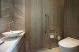 This luxurious bathroom boasts a sleek, modern design with a white vessel sink and a contemporary toilet.