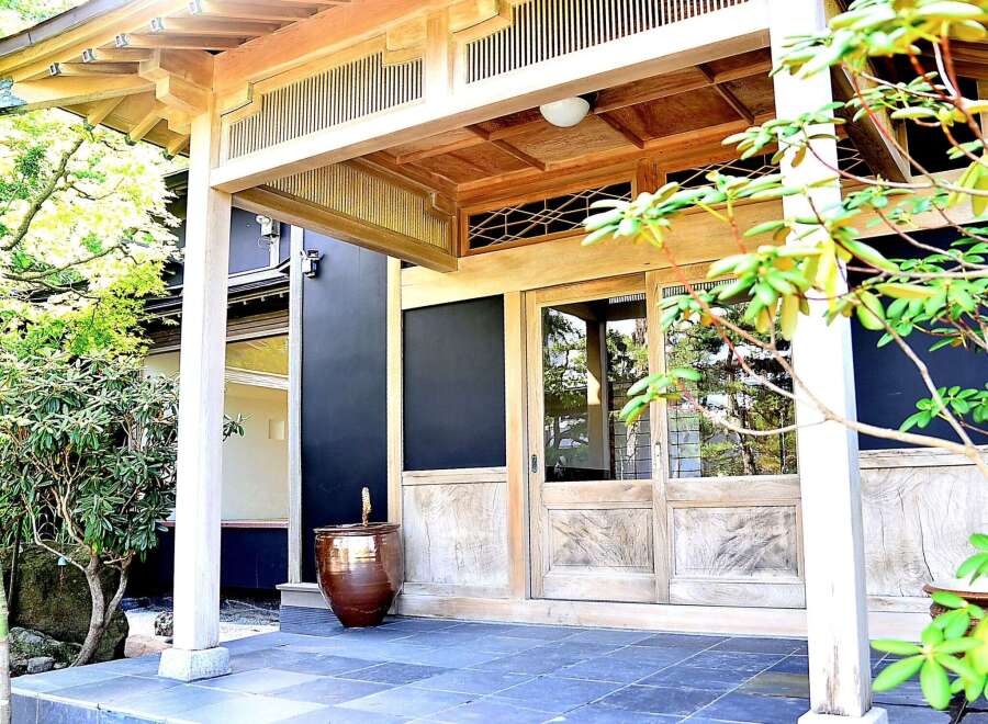 This stunning Japanese-style home features a spacious entryway with a beautiful wooden door and a serene garden view.