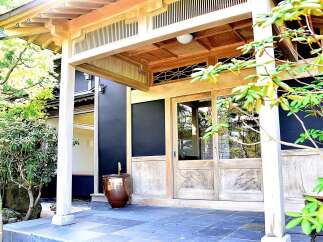 This stunning Japanese-style home features a spacious entryway with a beautiful wooden door and a serene garden view.
