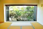 This serene space features tatami mats and a large window showcasing a lush Japanese garden.