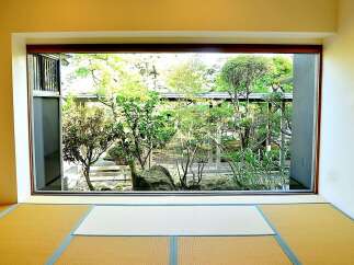 This serene space features tatami mats and a large window showcasing a lush Japanese garden.