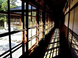 This stunning Japanese-style hallway boasts floor-to-ceiling windows offering breathtaking garden views.