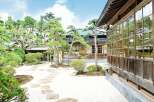 Discover serenity in this meticulously designed Japanese garden, featuring a traditional wooden house with expansive windows showcasing the lush greenery.