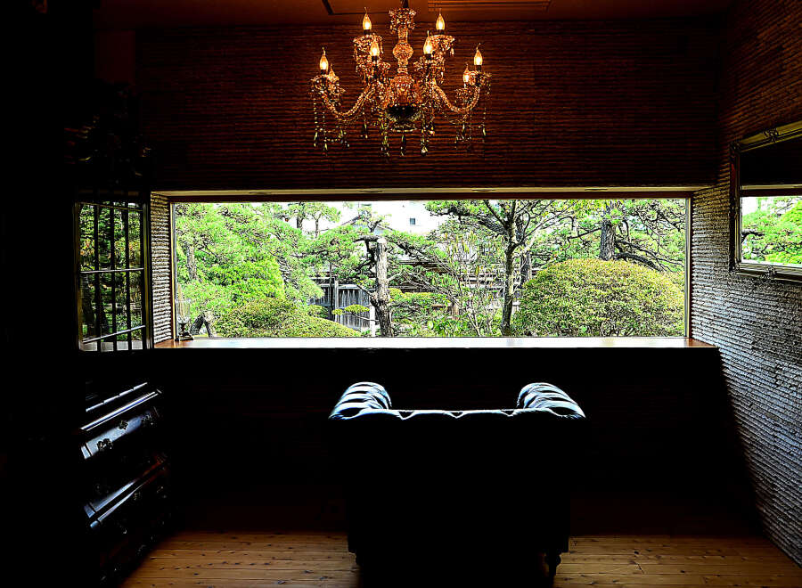Relax in this luxurious armchair, bathed in natural light from the expansive window overlooking a serene Japanese garden.
