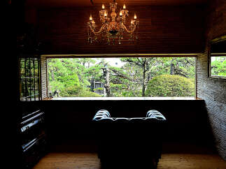 Relax in this luxurious armchair, bathed in natural light from the expansive window overlooking a serene Japanese garden.