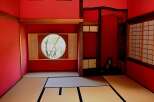 This serene Japanese-style room features tatami mats, shoji screens, and a circular window offering a tranquil garden view.