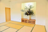 This serene Japanese-style room features tatami mats, a built-in wooden cabinet, and a stunning floral arrangement.