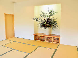 This serene Japanese-style room features tatami mats, a built-in wooden cabinet, and a stunning floral arrangement.